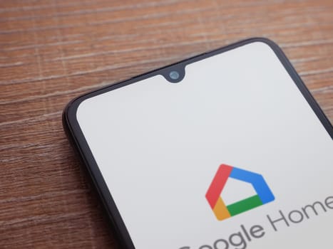 Lod, Israel - July 16,2023: Google Home app launch screen on smartphone on wooden background. Top view flat lay with copy space.