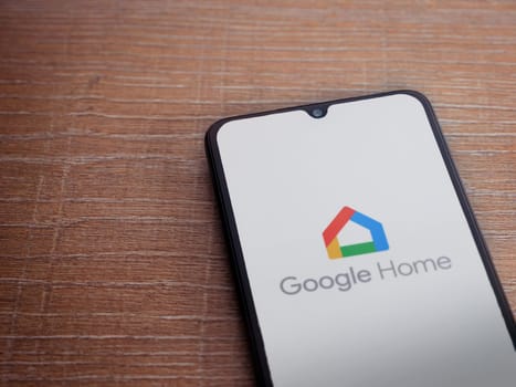 Lod, Israel - July 16,2023: Google Home app launch screen on smartphone on wooden background. Top view flat lay with copy space.