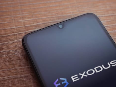 Lod, Israel - July 16,2023: Exodus app launch screen on smartphone on wooden background. Top view flat lay with copy space.