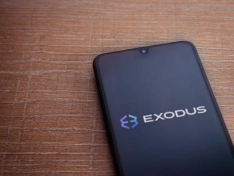 Lod, Israel - July 16,2023: Exodus app launch screen on smartphone on wooden background. Top view flat lay with copy space.