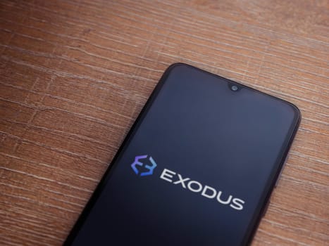 Lod, Israel - July 16,2023: Exodus app launch screen on smartphone on wooden background. Top view flat lay with copy space.