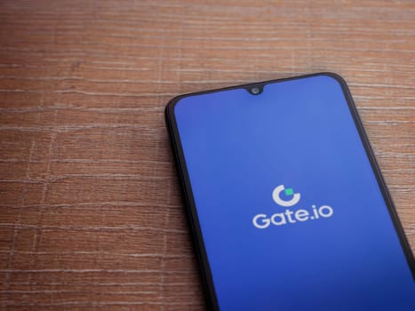 Lod, Israel - July 16,2023: Gate.io app launch screen on smartphone on wooden background. Top view flat lay with copy space.