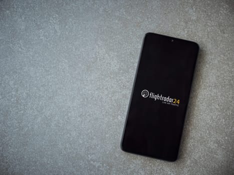 Lod, Israel - July 16,2023: Flightradar24 Flight Tracker app launch screen on smartphone on ceramic stone background. Top view flat lay with copy space.