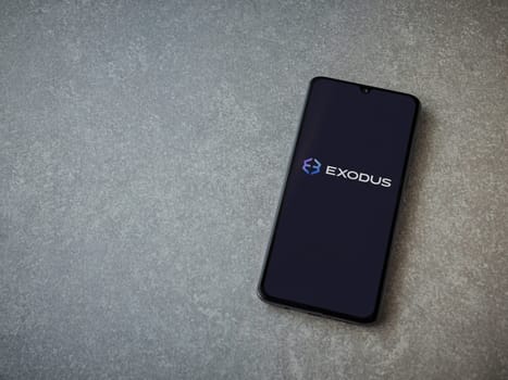 Lod, Israel - July 16,2023: Exodus app launch screen on smartphone on ceramic stone background. Top view flat lay with copy space.
