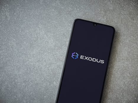 Lod, Israel - July 16,2023: Exodus app launch screen on smartphone on ceramic stone background. Top view flat lay with copy space.