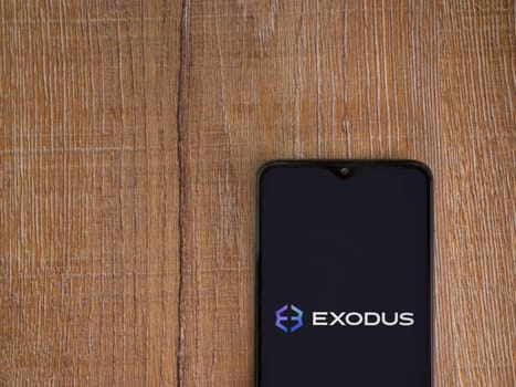 Lod, Israel - July 16,2023: Exodus app launch screen on smartphone on wooden background. Top view flat lay with copy space.