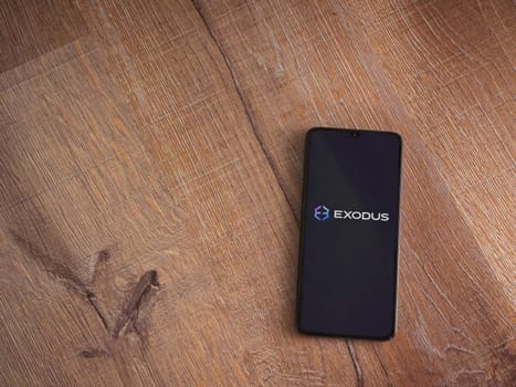 Lod, Israel - July 16,2023: Exodus app launch screen on smartphone on wooden background. Top view flat lay with copy space.
