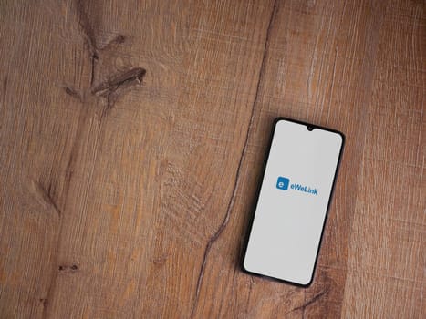 Lod, Israel - July 16,2023: eWeLink app launch screen on smartphone on wooden background. Top view flat lay with copy space.