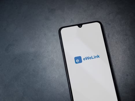 Lod, Israel - July 16,2023: eWeLink app launch screen on smartphone on dark marble stone background. Top view flat lay with copy space.