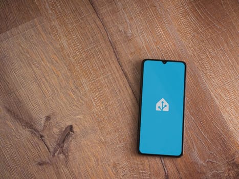 Lod, Israel - July 16,2023: Home Assistant app launch screen on smartphone on wooden background. Top view flat lay with copy space.