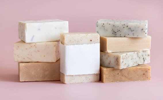 Beige and brown handmade soap bars on light pink close up, soap packaging mockup, copy space. Natural herbal products for for face and body care. Organic handmade skincare products