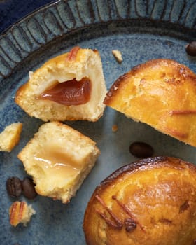 Pasticciotto leccese pastry filled with egg custard cream and sour cherry jam. Pieces of pasticiotto on a dark blue plate, typical apulian breakfast, top view. Table decorated with coffee beans