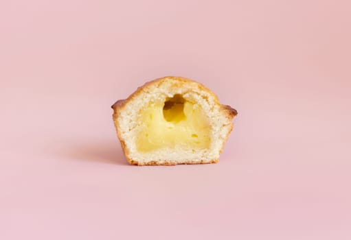 Pasticciotto leccese pastry filled with egg custard cream, typical sweet from Lecce, Italy. Half of baked pasticiotto on a pink, apulian breakfast, close up