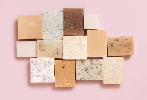 Beige and brown handmade soap bars on light pink top view, copy space. Natural herbal products for Spa and skin care. Using organic handmade skincare products in everyday routine