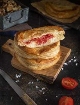Rustico traditional puff pastry stuffed with bechamel sauce, tomato and mozzarella cheese, close up on a dark table. Traditional street food from Salento, Lecce, Italy