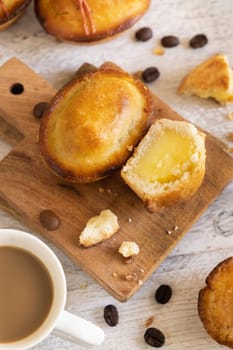 Pasticciotto leccese pastry filled with egg custard cream, typical sweet from Lecce, Italy. Pieces of pasticiotto on a wooden board, apulian breakfast with coffee cup, top view