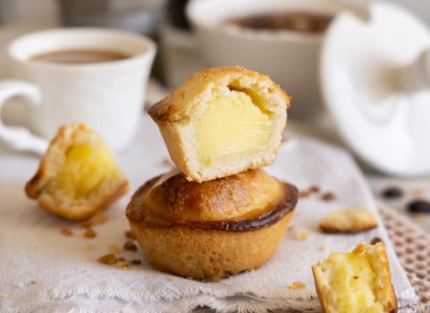 Pasticciotto leccese pastry filled with egg custard cream, typical sweet from Lecce, Italy. Pieces of pasticiotto on a beige napkin, apulian breakfast with coffee close up