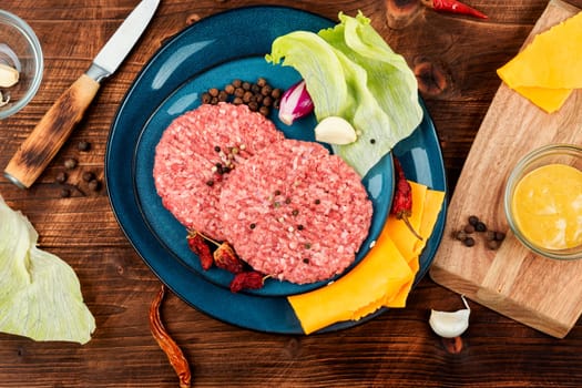 Fresh with seasoning raw minced beef steak burgers. Cooking burger. Raw steak cutlets. Wooden background.
