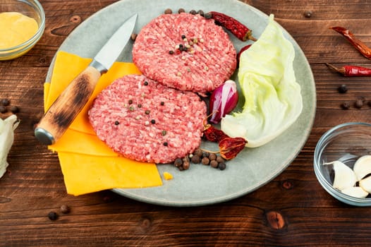 Fresh with seasoning raw minced beef steak burgers. Cooking burger. Raw steak cutlets. Wooden background.