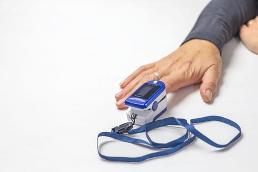 Female hands measure pulse and blood   oxygenation with a compact electronic pulse oximeter. There is enough space for your text on the photo.
