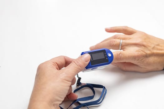Female is checking data on a compact electronic pulse oximeter. Display is blank for your data.
