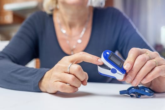 Woman is inserting finger into compact electronic pulse oximeter.  Horizontally.