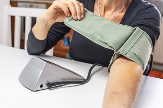 Woman is preparing older type of Blood Pressure Monitor on her hand. Horizontally.