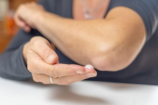Home treatment concept. Female is ready to apply healing ointment to her elbow. Horizontally.
