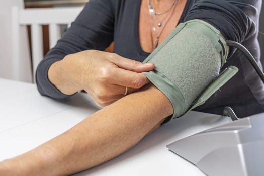 Woman is showing the correct use of a older type blood pressure monitor.