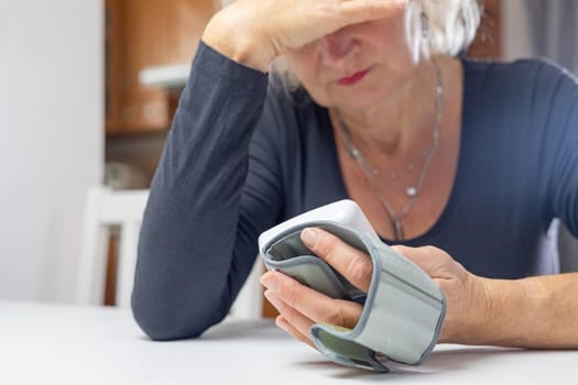 Woman lis looking at the results of blood pressure measurement with her hand on her forehead.