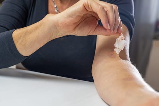 Home treatment concept. Woman is pulling  a adhesive plaster  from the hand. Horizontally.