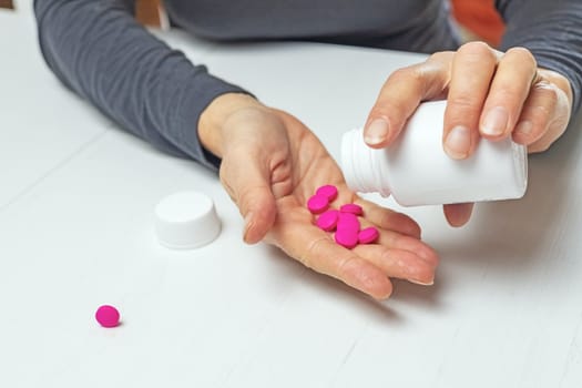 Healthcare and medical concept. Woman pours out medicine into her hand.