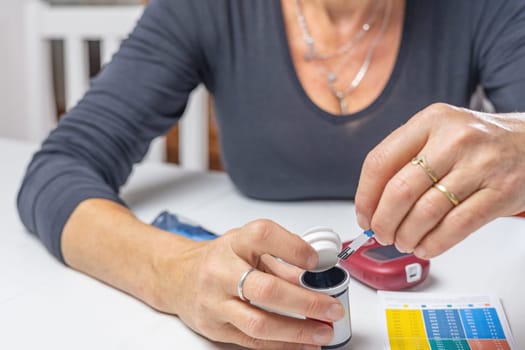 Woman  is holding glucometer strips  for measuring blood sugar.level. Horizontally.