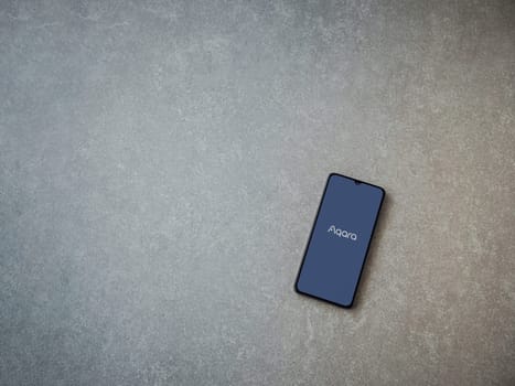 Lod, Israel - July 16,2023: Aqara Home app launch screen on smartphone on ceramic stone background. Top view flat lay with copy space.