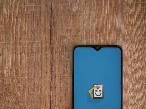 Lod, Israel - July 16,2023: Automate app launch screen on smartphone on wooden background. Top view flat lay with copy space.