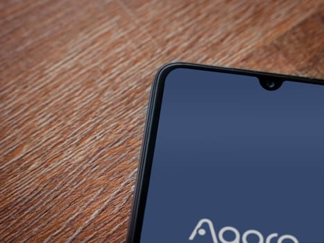 Lod, Israel - July 16,2023: Aqara Home app launch screen on smartphone on wooden background. Top view flat lay with copy space.