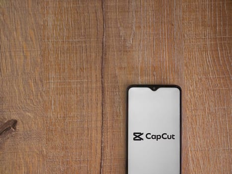 Lod, Israel - July 16,2023: CapCut app launch screen on smartphone on wooden background.. Top view flat lay with copy space.