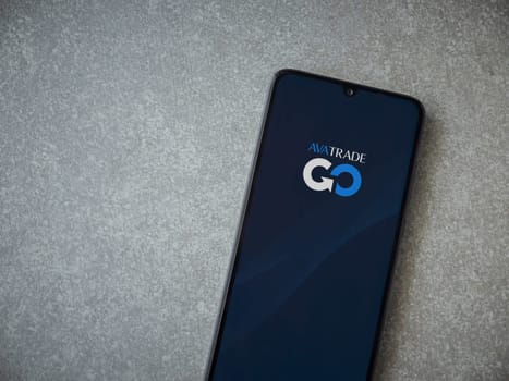 Lod, Israel - July 16,2023: Avatrade app launch screen on smartphone on ceramic stone background. Top view flat lay with copy space.