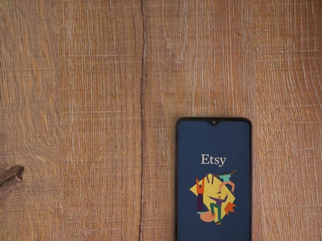 Lod, Israel - July 16,2023: Etsy Seller app launch screen on smartphone on wooden background. Top view flat lay with copy space.