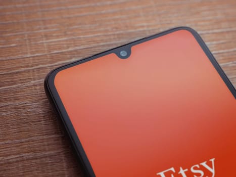 Lod, Israel - July 16,2023: Etsy app launch screen on smartphone on wooden background. Top view flat lay with copy space.
