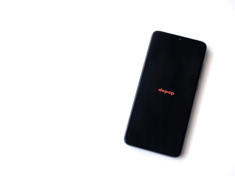 Lod, Israel - July 16,2023: Depop app launch screen on smartphone on white background. Top view flat lay with copy space.