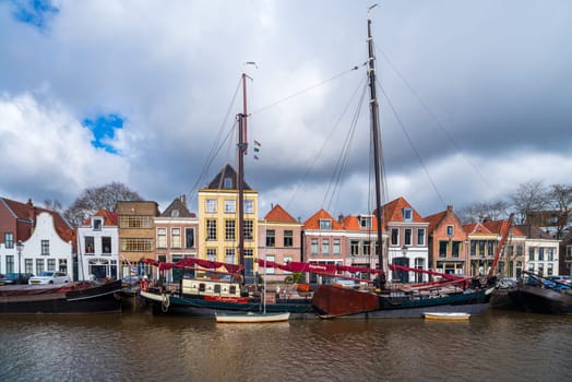 ZWOLLE, NETHERLANDS - MARCH 14, 2021: Old boats and barges in front of some nice gabled houses in the dutch city of Zwolle