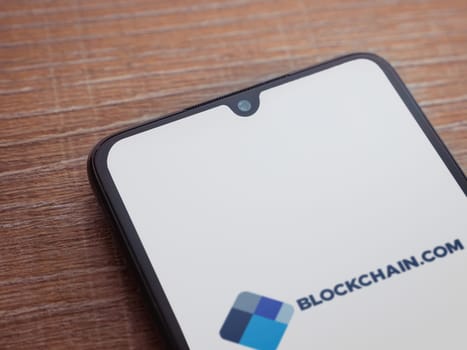 Lod, Israel - July 16,2023: Blockchain.com app launch screen on smartphone on wooden background. Top view flat lay with copy space.