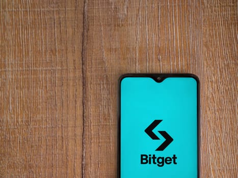 Lod, Israel - July 16,2023: Bitget app launch screen on smartphone on wooden background. Top view flat lay with copy space.