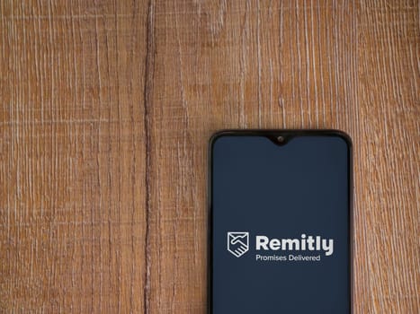 Lod, Israel - July 16,2023: Remitly app launch screen on smartphone on wooden background. Top view flat lay with copy space.