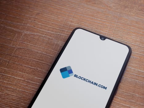 Lod, Israel - July 16,2023: Blockchain.com app launch screen on smartphone on wooden background. Top view flat lay with copy space.