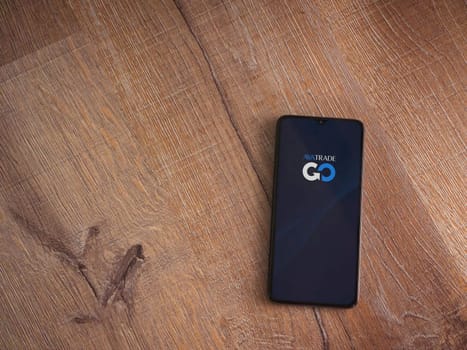 Lod, Israel - July 16,2023: Avatrade app launch screen on smartphone on wooden background. Top view flat lay with copy space.
