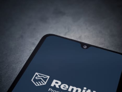 Lod, Israel - July 16,2023: Remitly app launch screen on smartphone on dark marble stone background. Top view flat lay with copy space.