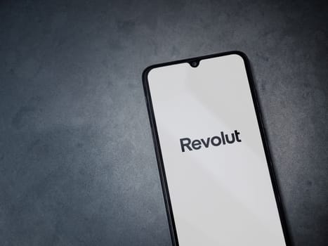 Lod, Israel - July 16,2023: Revolut app launch screen on smartphone on dark marble stone background. Top view flat lay with copy space.
