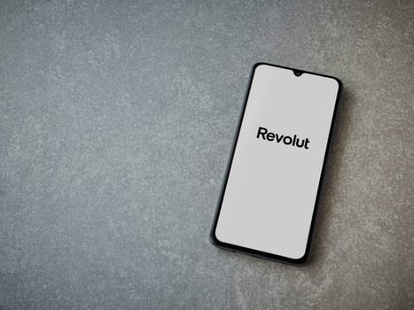Lod, Israel - July 16,2023: Revolut app launch screen on smartphone on ceramic stone background. Top view flat lay with copy space.